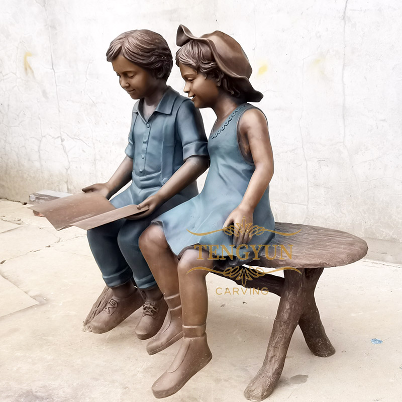 Boy and girl statue sitting on bench reading sculpture (1)